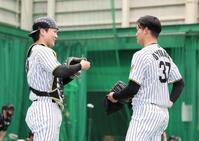 　ブルペンでの投球を終えて話し合う伏見（左）と及川