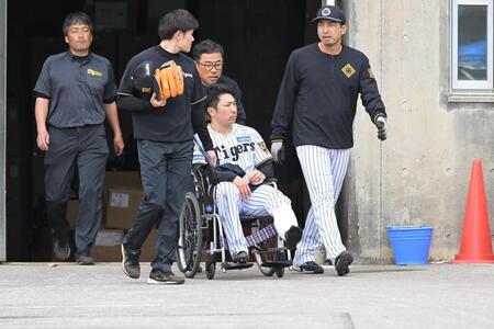 車椅子で運ばれる石井