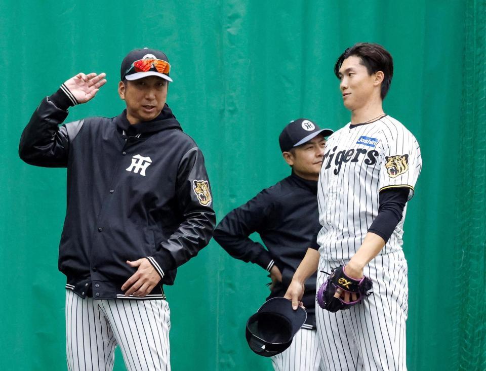 ブルペンで藤川監督（左）から指導を受ける湯浅（撮影・西田忠信）