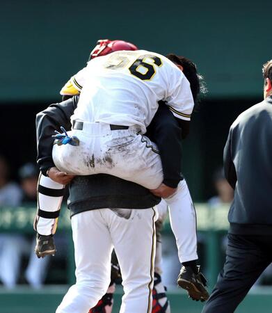 ６回、自打球を受けた百崎はおんぶされベンチに戻る（撮影・山口登）