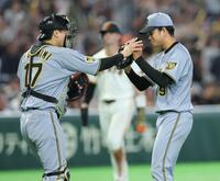 完封勝利で伏見（左）とタッチを交わす高橋（撮影・西岡正）