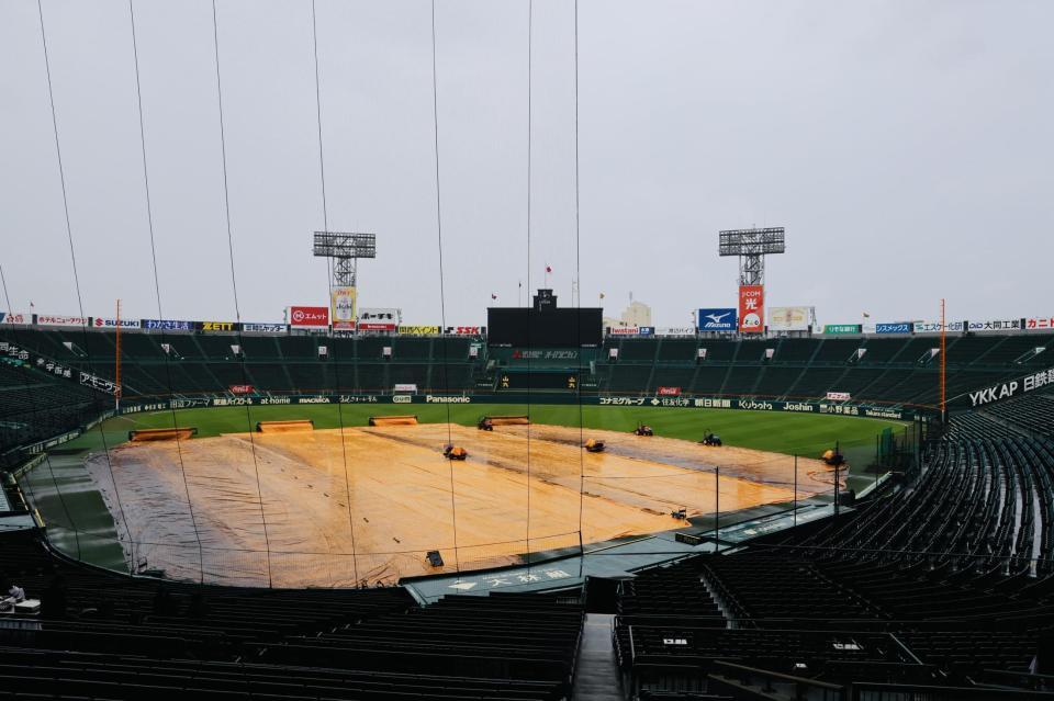雨が降り続き、グラウンドにはシートが敷かれている（撮影・山口登）