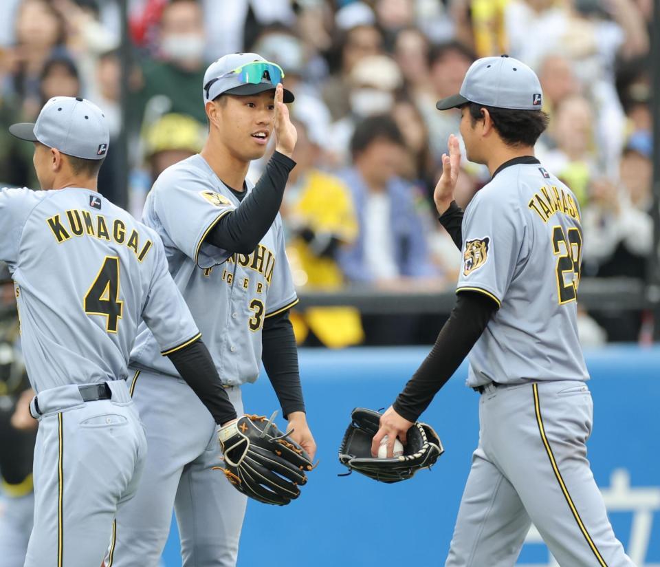 最前列で選手を迎え、高橋（右）とタッチを交わす岡城（撮影・西岡正）