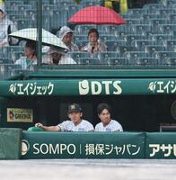 雨のため試合が遅れ、ベンチからグラウンドを見つめる立石（左）と岡城（撮影・田中太一）