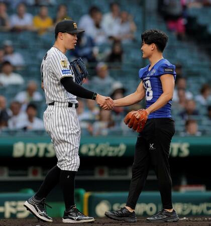 ファーストピッチセレモニーに登場したパナソニックインパルス・桑田理介（右）と握手をする佐藤輝（撮影・西田忠信）