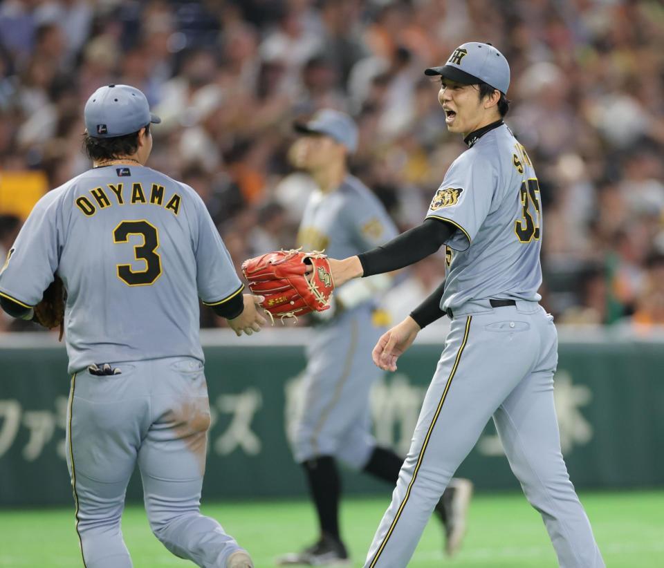 ５回、キャベッジを右飛に打ち取ってピンチを脱し、大山（左）とタッチを交わす才木（撮影・西岡正）