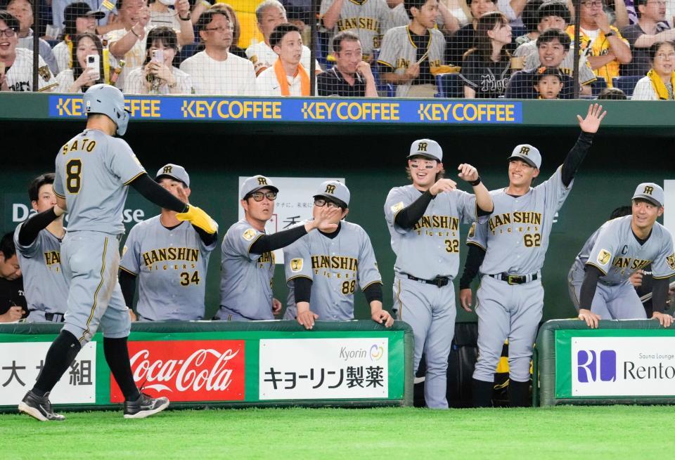 ４回、大山の適時二塁打で生還した佐藤（手前）を迎える阪神ナイン