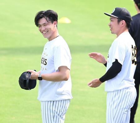 練習中、球場内にバースデーソングが流れ、照れ笑いする湯浅。右は祝福する石井（撮影・高部洋祐）