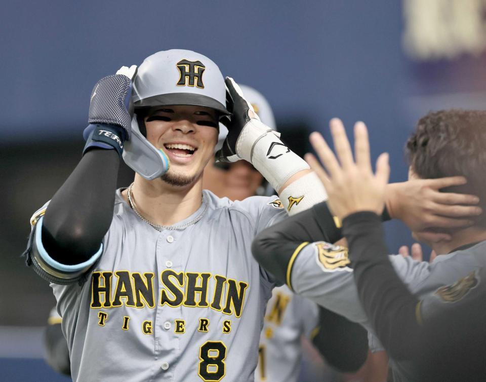 　７回、逆転２ランを放った佐藤輝はナインに迎えられ笑顔を見せる（撮影・田中太一）