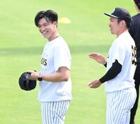 練習中、球場内にバースデーソングが流れ、照れ笑いする湯浅。右は祝福する石井（撮影・高部洋祐）