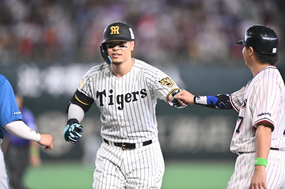 ６回、中前打を放ち一塁コーチャーを務める清水（右）とグータッチを交わす佐藤輝（撮影・開出牧）