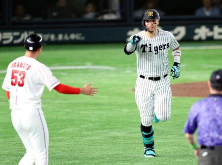 　１回、先制ソロを放ち、一塁コーチの岡本を指さす佐藤輝（撮影・金田祐二）