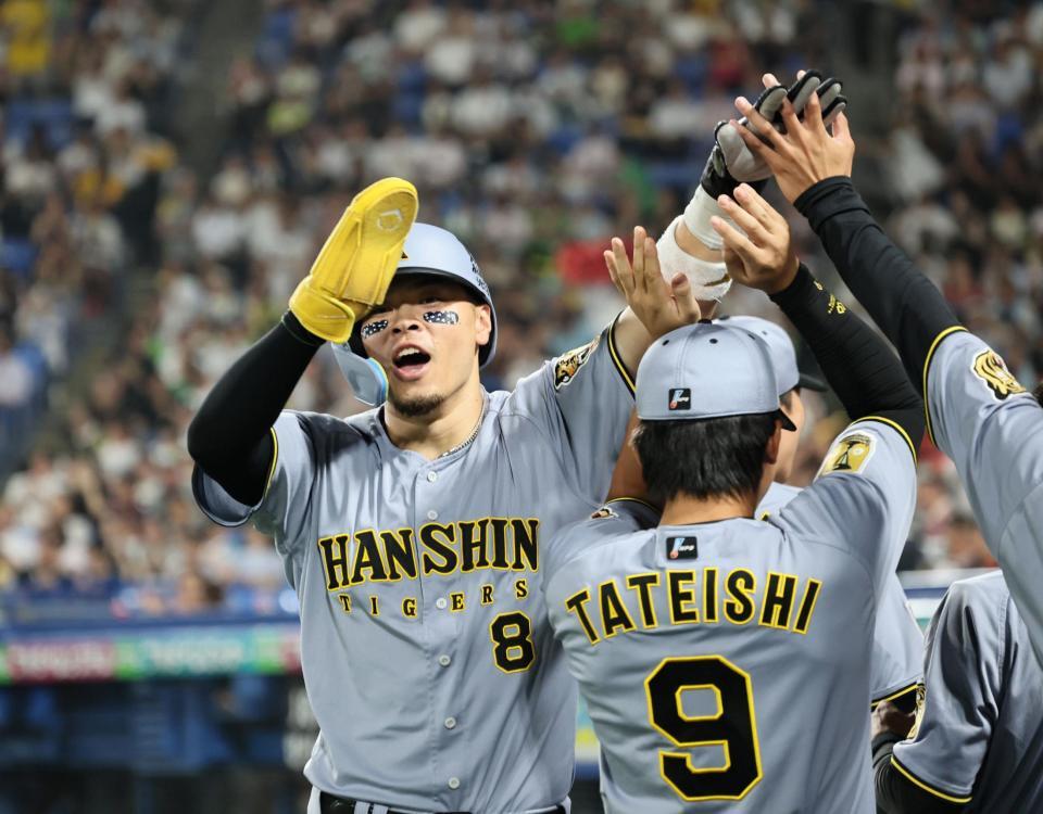 ７回、生還しナインに迎えられる佐藤輝（撮影・田中太一）