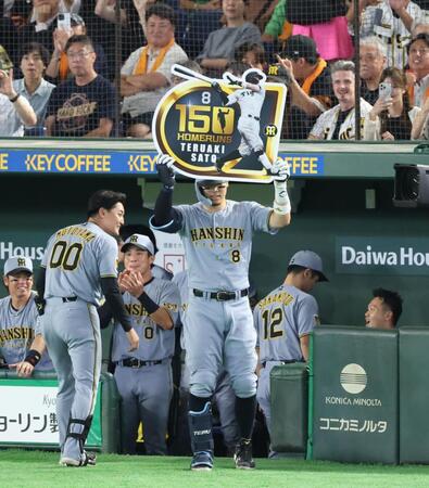 ７回、右中間にプロ入り通算１５０号となるソロを放ちボードを掲げる佐藤輝（撮影・金田祐二）