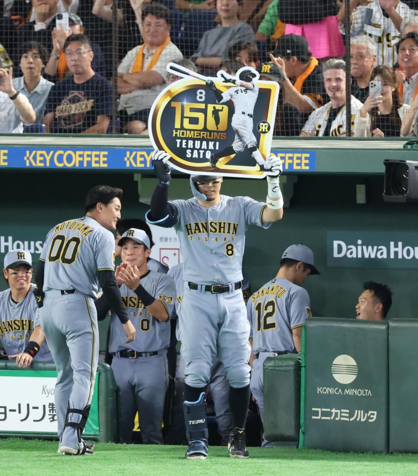 ７回、右中間にプロ入り通算１５０号となるソロを放ちボードを掲げる佐藤輝（撮影・金田祐二）