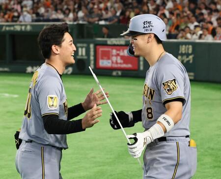 ７回、１５０号を放った阪神・佐藤輝明にボードを手渡す阪神・元山飛優＝１２日