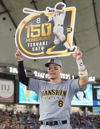 お立ち台でボードを掲げる佐藤輝＝１２日