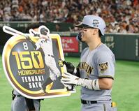 ７回、プロ通算１５０号を放った佐藤輝はボードを手に笑顔を見せる＝１２日