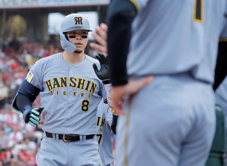 広島戦の１回、先制２ランを放ち、ナインとタッチを交わす佐藤輝（撮影・西田忠信）＝１６日