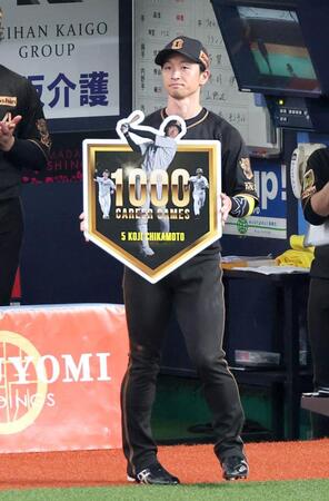 通算１０００試合出場を達成し、記念ボードを掲げる近本（撮影・立川洋一郎）
