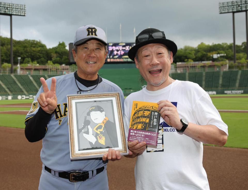 切り絵作家の民井達也さん（右）から自身の肖像と、著作を贈られ、笑顔の平田２軍監督（撮影・坂部計介）
