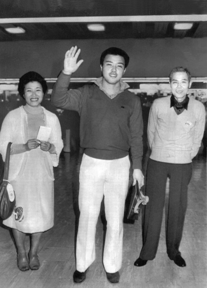 「行ってきます」と手を振る阪神・岡田彰布は両親のサカヨさん、勇郎さんと共にハワイへ慰安旅行に出発＝１９８１（昭和５６）年１２月３０日、大阪国際空港