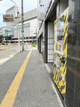 広島駅（奥）近くに設置されている阪神グッズの自販機（右）