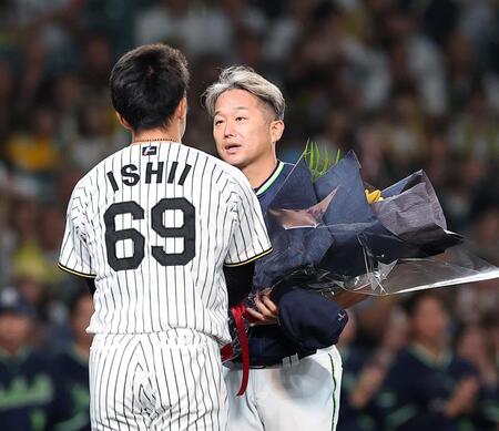 今季限りで引退する石川は石井（左）から花束を受け取る（撮影・西田忠信）