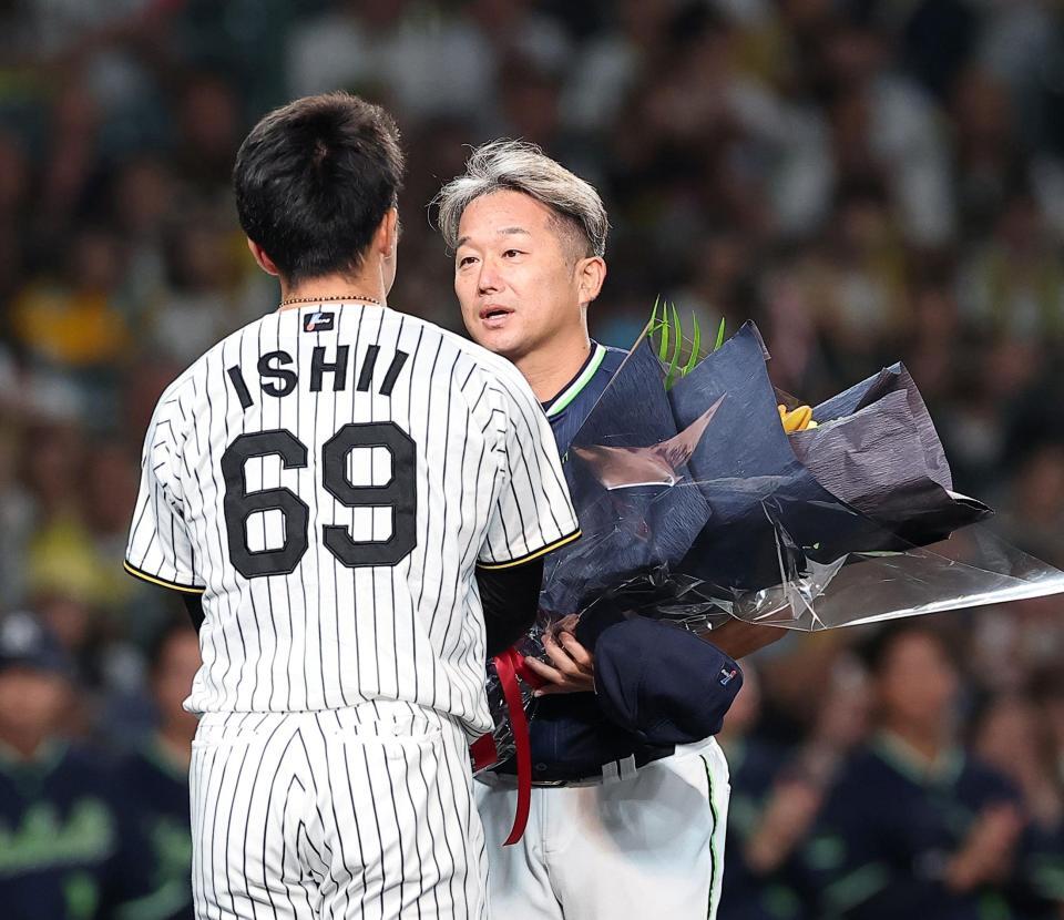 今季限りで引退する石川は石井（左）から花束を受け取る（撮影・西田忠信）