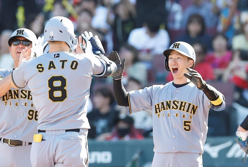 ３回阪神２死一、二塁、３ランを放った阪神・佐藤輝明を迎える阪神・近本光司（右）＝マツダスタジアム（撮影・西田忠信）