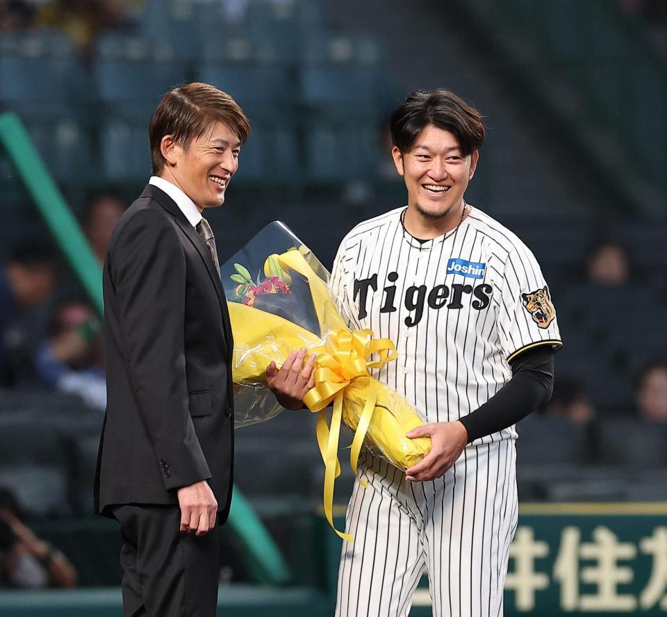 能見篤史氏（左）から花束を受け取り笑顔の岩貞（撮影・西田忠信）