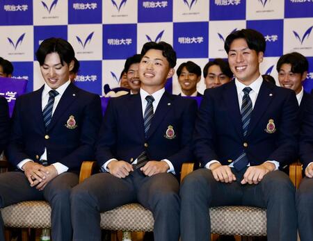 阪神から１位指名を受け、笑顔を見せる明大・榊原七斗（中央）＝撮影・中島達哉