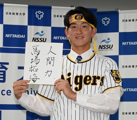 座右の銘をかいた色紙を手に笑顔を見せる阪神２位指名の日体大・馬場拓海（撮影・持木克友）