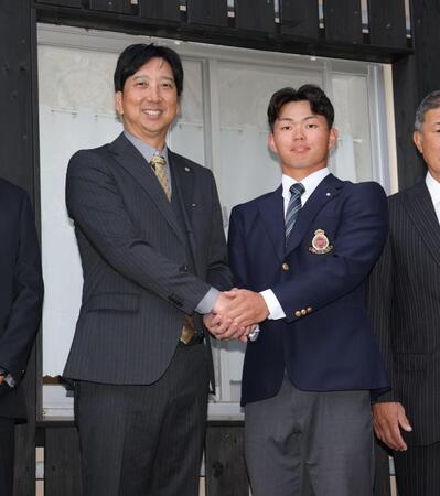 藤川監督（左）と握手を交わす阪神１位の明大・榊原七斗（撮影・西岡正）