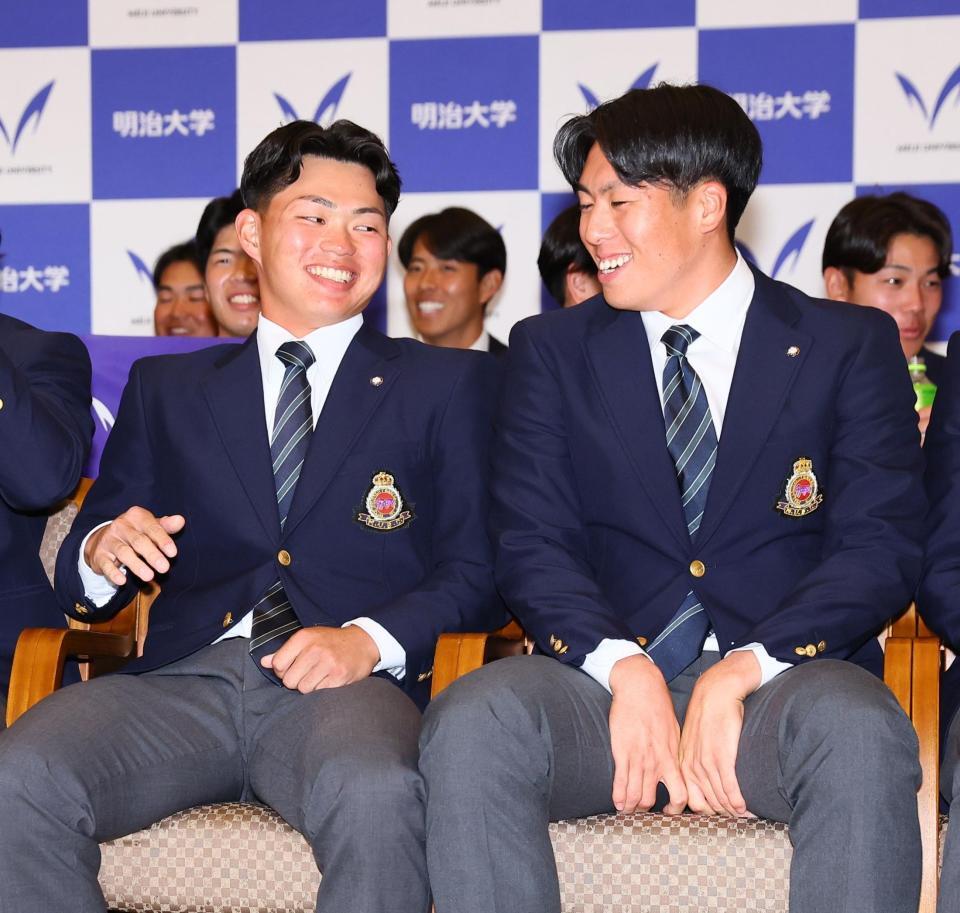 阪神からドラフト１位指名を受け、松本直（右）から祝福され、笑顔を見せる明大・榊原七斗（撮影・中島達哉）
