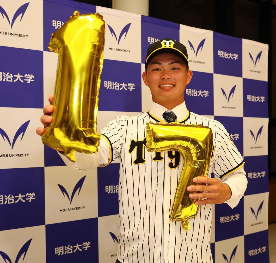 阪神からドラフト１位指名を受け、同大から１７年連続指名にちなんだバルーンを手に記念撮影に応じる明大・榊原七斗（撮影・中島達哉）