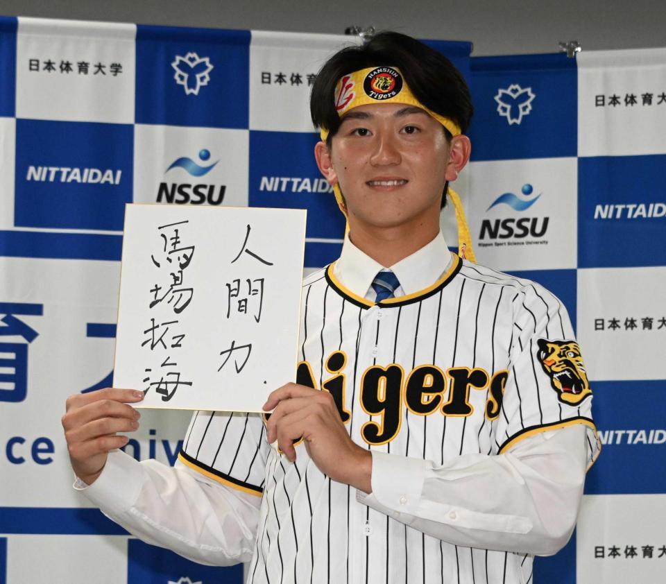 座右の銘をかいた色紙を手に笑顔を見せる阪神２位指名の日体大・馬場拓海（撮影・持木克友）