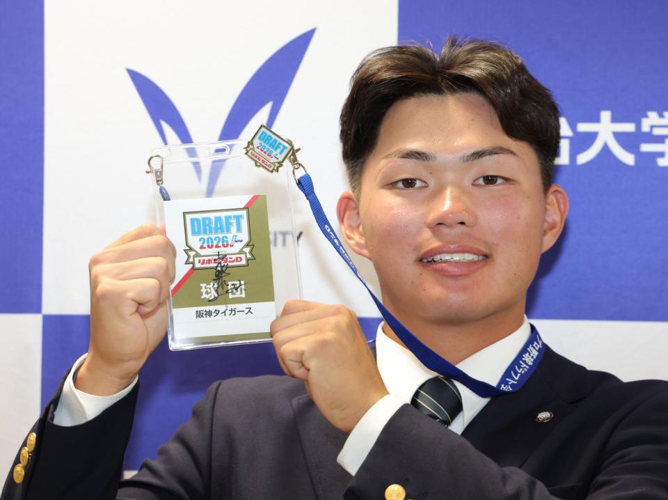 藤川球児監督のサインが入ったドラフトのパスを手に笑顔を浮かべる阪神１位の明大・榊原七斗（撮影・西岡正）