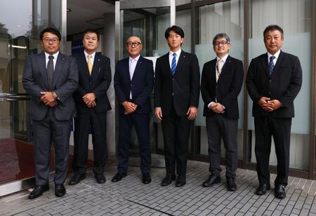 指名あいさつで記念撮影に応じる東編成ディレクター、平塚スカウト、畑山統括スカウト、日体大・馬場拓海、ドラフト２位指名の日体大・大石部長、日体大・古城監督（撮影・中島達哉）