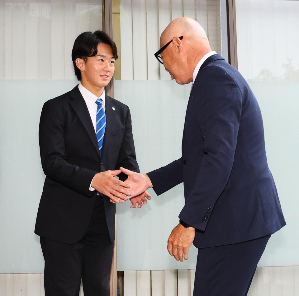 指名あいさつに訪れた畑山統括スカウト（右）と握手を交わす日体大・馬場拓海（撮影・中島達哉）