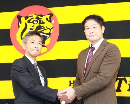 竹内孝行球団副本部長（左）と握手する岡崎太一ファームバッテリーコーチ（撮影・西田忠信）
