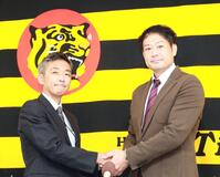 竹内孝行球団副本部長（左）と握手する岡崎太一ファームバッテリーコーチ（撮影・西田忠信）