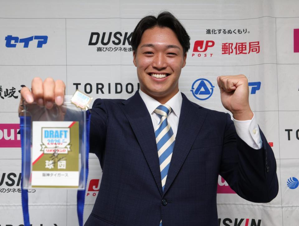 贈られたドラフト会場のＩＤを手に、笑顔を見せる阪神ドラフト７巡目・石井康輝（撮影・坂部計介）