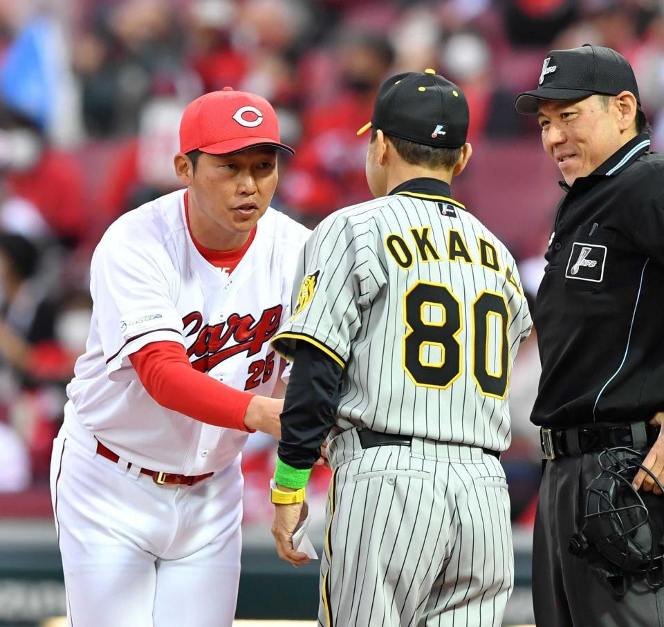 　メンバー表交換で岡田監督（８０）と握手を交わす新井監督