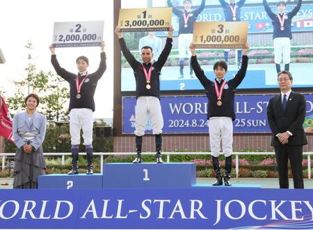 　表彰台で賞金ボードを掲げる（左から）個人戦２位の武豊、１位のモレイラ、３位の坂井。左端はプレゼンターの阿部詩