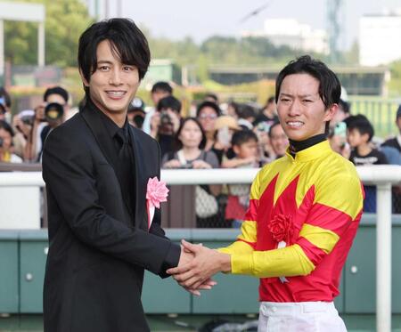 　菅原明（右）と握手を交わすプレゼンターの溝端淳平