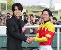 　菅原明（右）と握手を交わすプレゼンターの溝端淳平