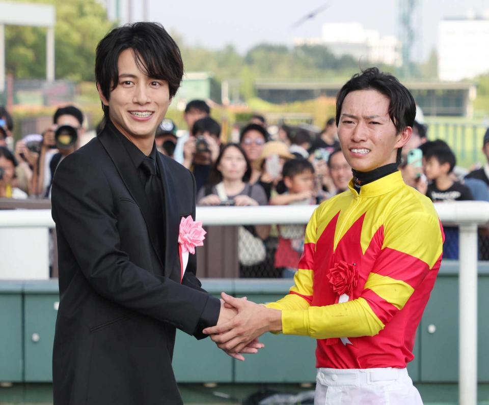 　菅原明（右）と握手を交わすプレゼンターの溝端淳平