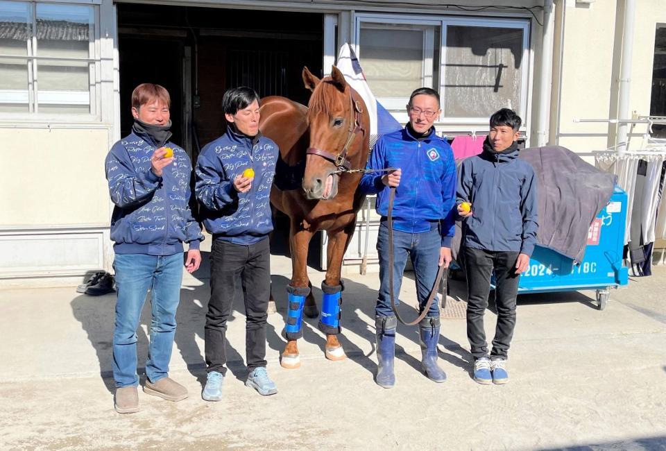 　現役を引退し、美浦トレセンを退厩したレモンポップとレモンを手に記念撮影する田中博師（右）ら関係者