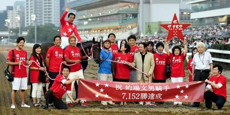　地方競馬最多勝記録を達成して記念撮影する的場文と関係者（赤い星のボードを挙げているのは妻の尚子さん）＝２０１８年８月